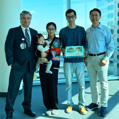 Team members holding a baby and a cake
