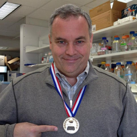 Dr. Thomas Carroll pointing to a medal
