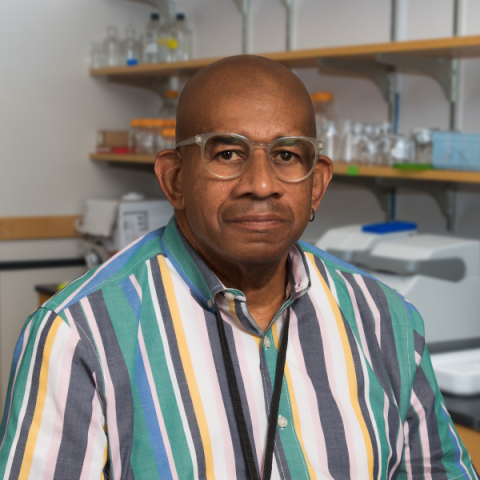 Gerald Strickland wearing a striped shirt, standing in a laboratory