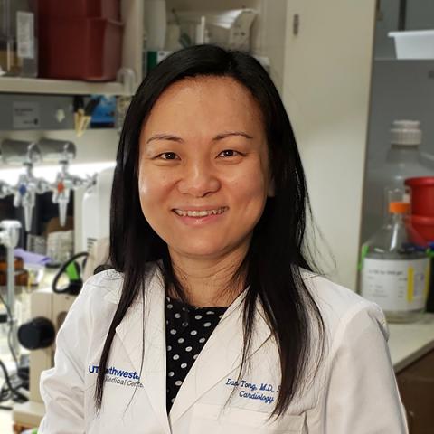 Dr. Dan (Amanda) Tong in a white coat standing in her lab