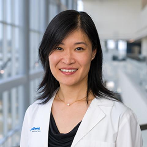 Smiling woman with long dark hair, wearing a lab coat.