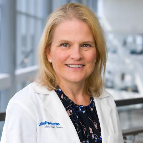 Smiling woman with blond hair, wearing a white lab coat.