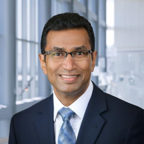 Dr. Mambarambath Jaleel wearing a dark blue suit and patterned blue tie