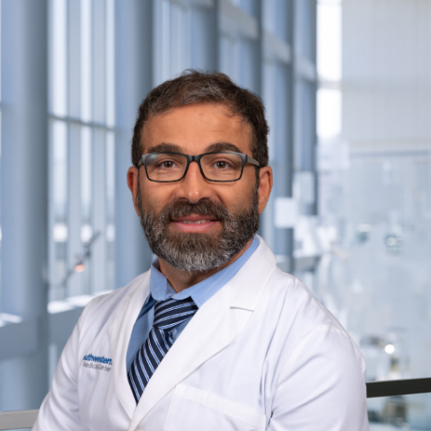 a man with a beard wearing glasses and a white lab coat