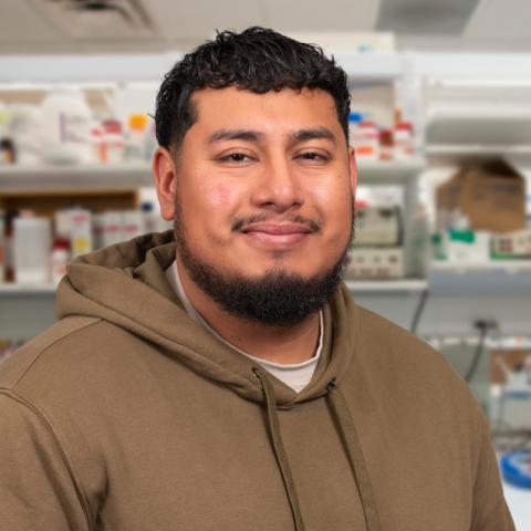 David Bautista wearing a tan hoodie standing in a research laboratory