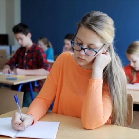 female student in a classroom writing at a desk